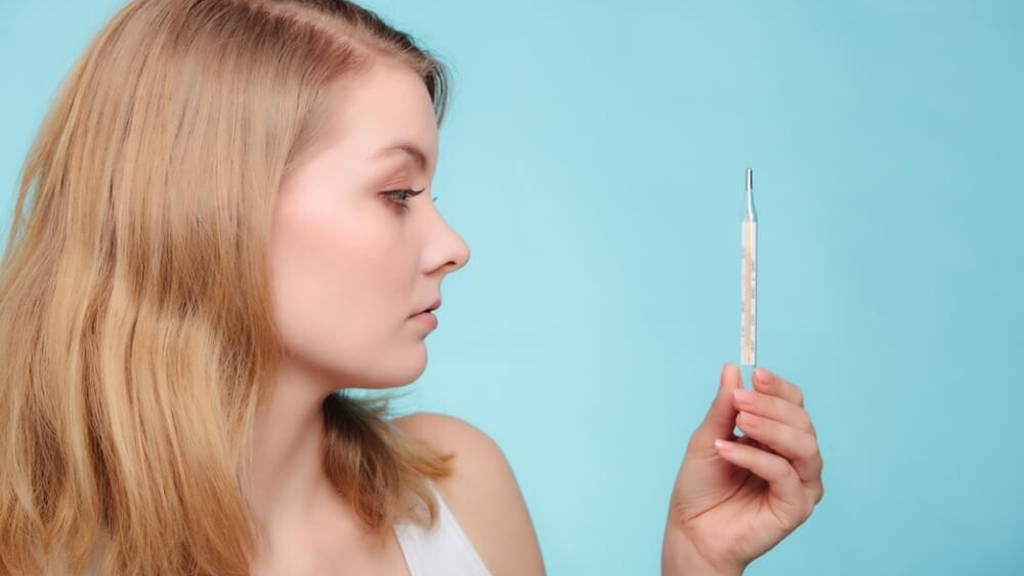 Flu. Sick girl with fever checking thermometer.