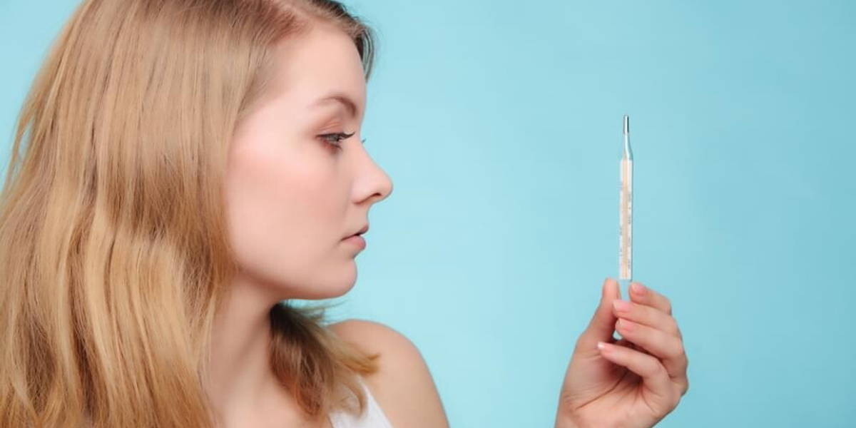 Flu. Sick girl with fever checking thermometer.