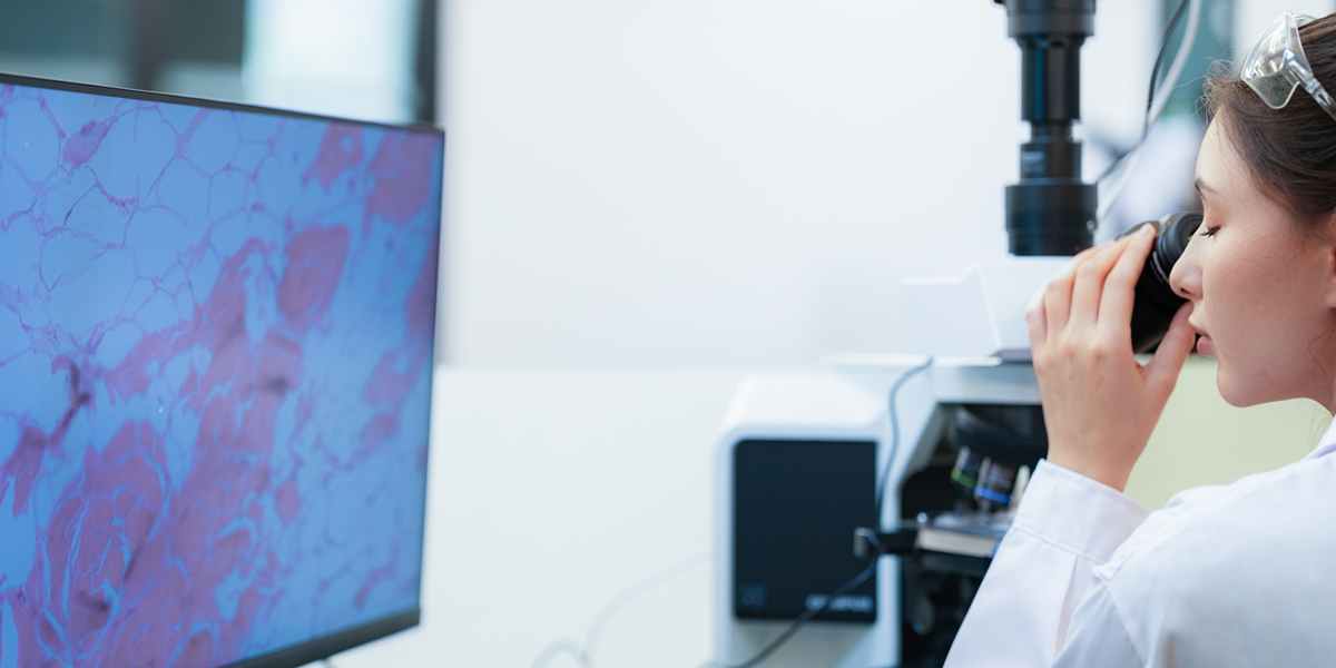 Onderzoeker bekijkt cellen onder microscoop