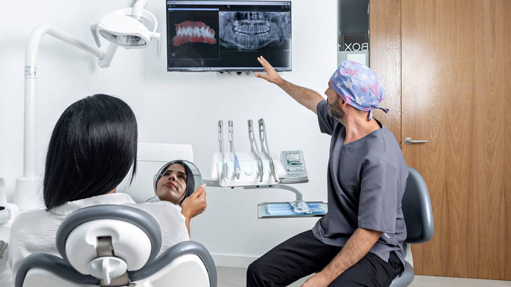Dentist showing a x-ray to a patinet that is sitting on a chair in a clinic