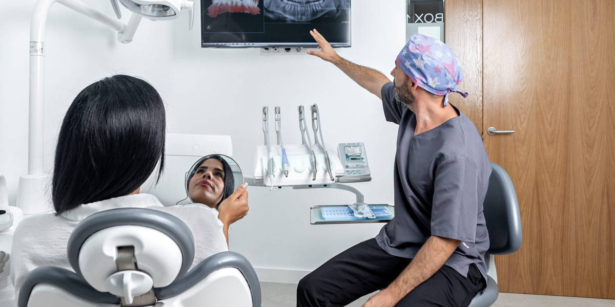 Dentist showing a x-ray to a patinet that is sitting on a chair in a clinic