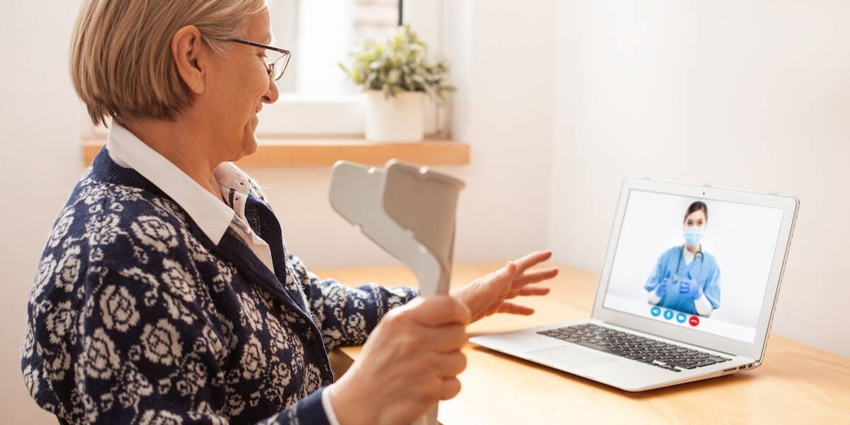 Oudere vrouw videocallt met arts op laptop