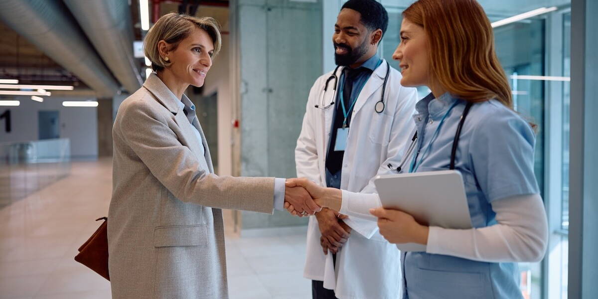 Vrouw geeft een hand aan twee artsen