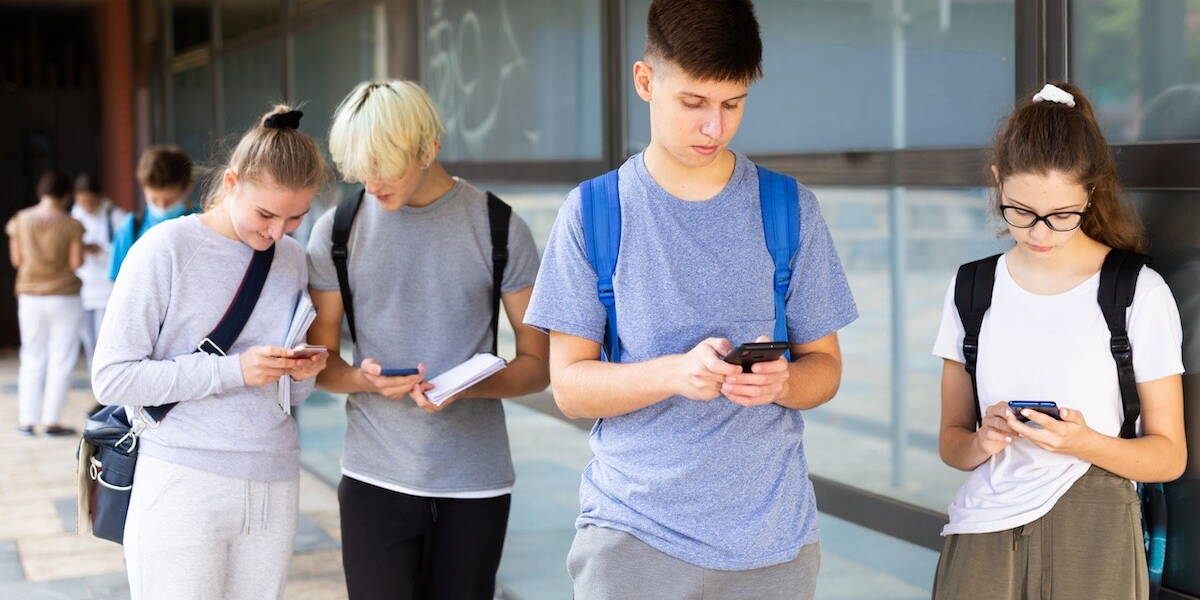 Vier jongeren die op smartphone kijken
