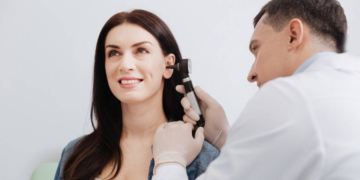 Arts kijkt in oor patient