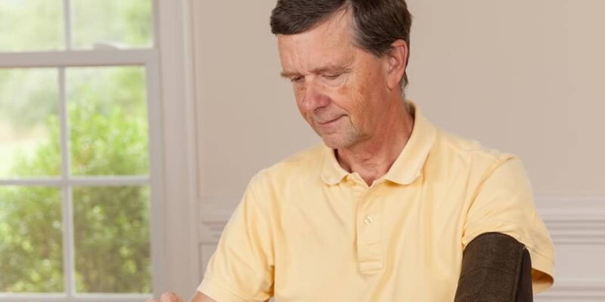 Senior man taking blood pressure at home