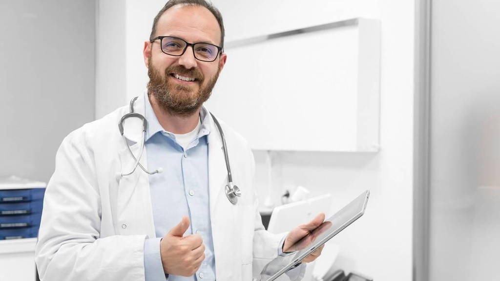Friendly male doctor smiling and giving thumb up sign