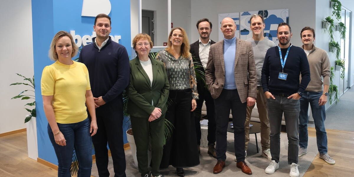 Groep lachende mensen staan voor een bord van Better