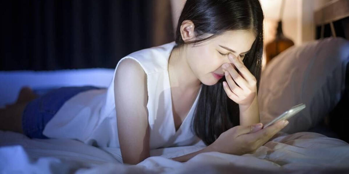 vrouw-bed-smartphone-pijn