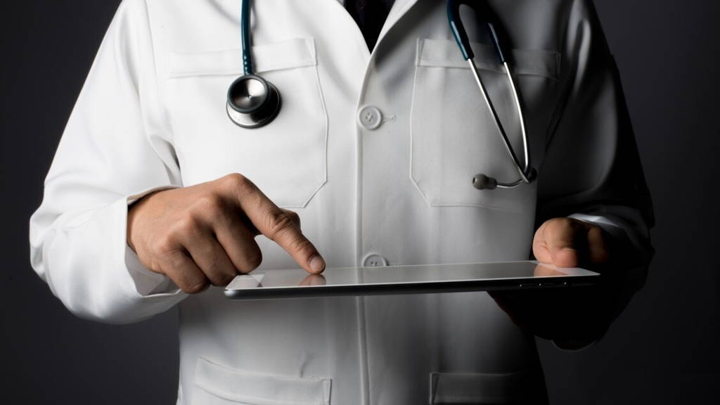Young medical doctor holding a tablet pc isolated on grey.