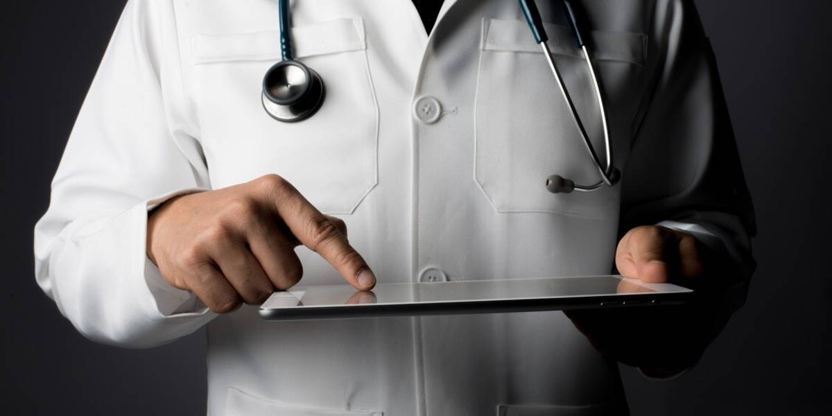 Young medical doctor holding a tablet pc isolated on grey.