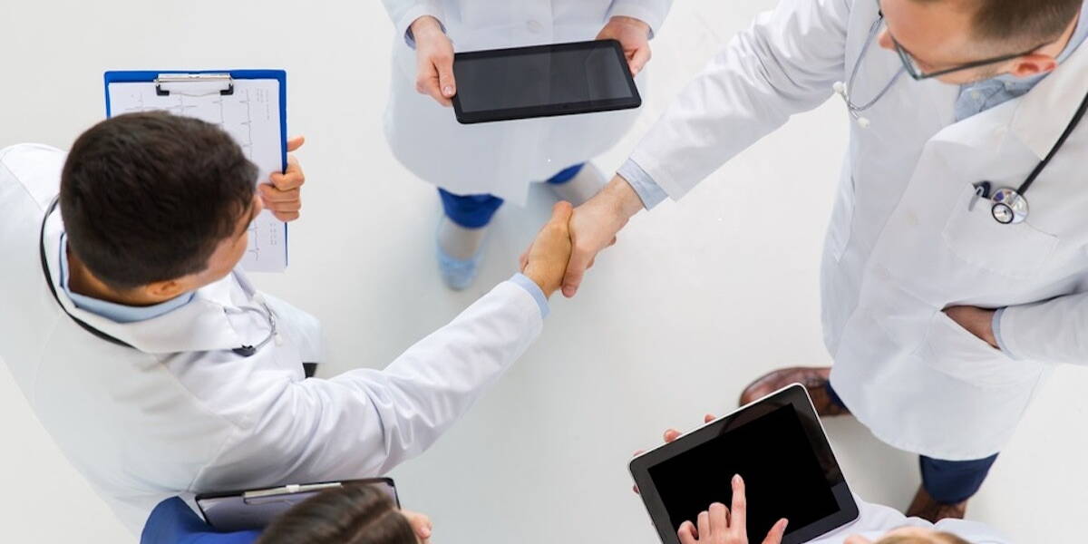 doctors with tablet pc doing handshake at hospital