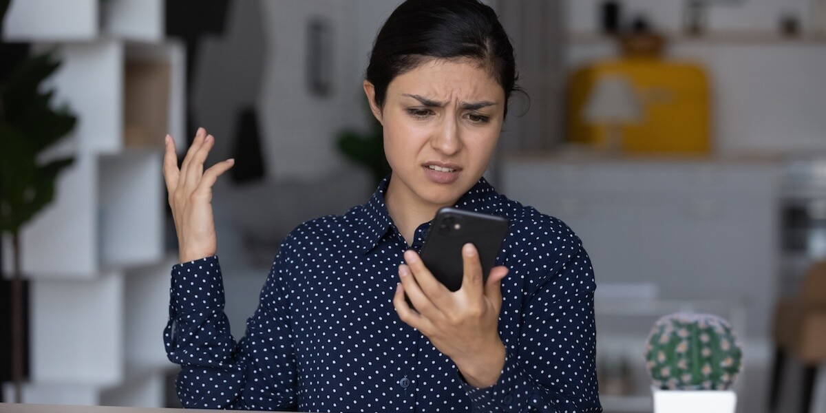 Vrouw kijkt geïrriteerd naar mobiele telefoon