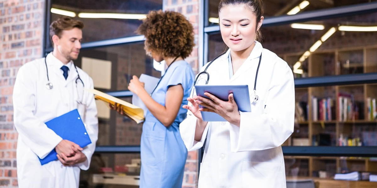 Female doctor using digital tablet near library and colleagues standing behind and discussing