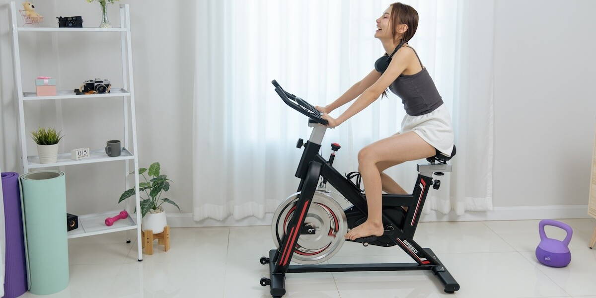 Vrouw traint op hometrainer thuis