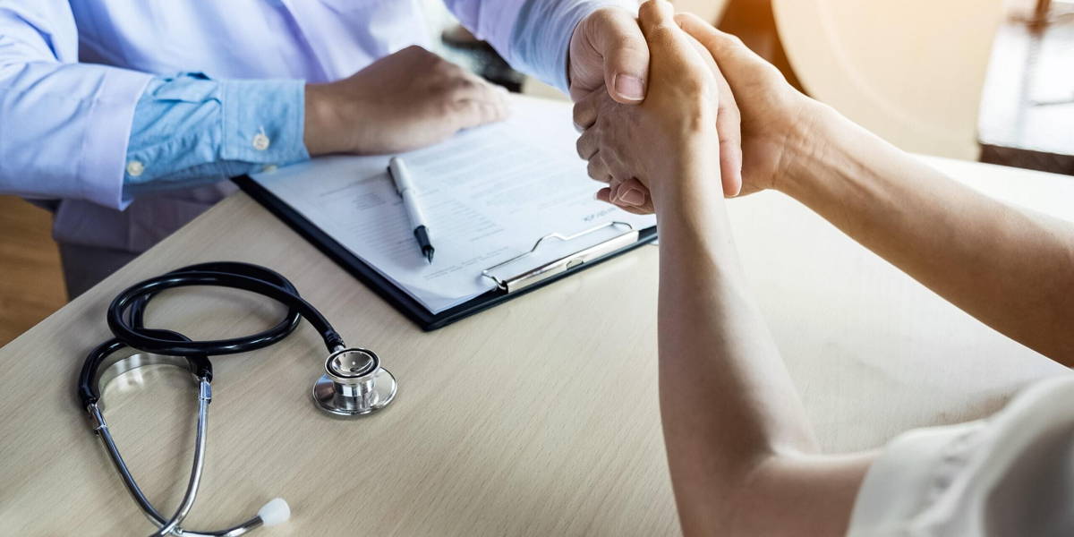 Doctor shakes hands at medical office with patient, wearing glas