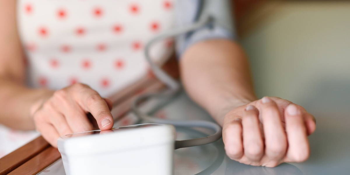 Woman measuring her own blood pressure at home.