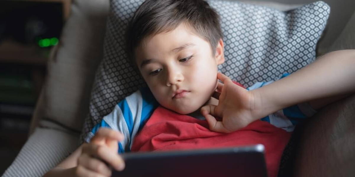 Young boy holding tablet looking out deep in thought, Unhappy ki