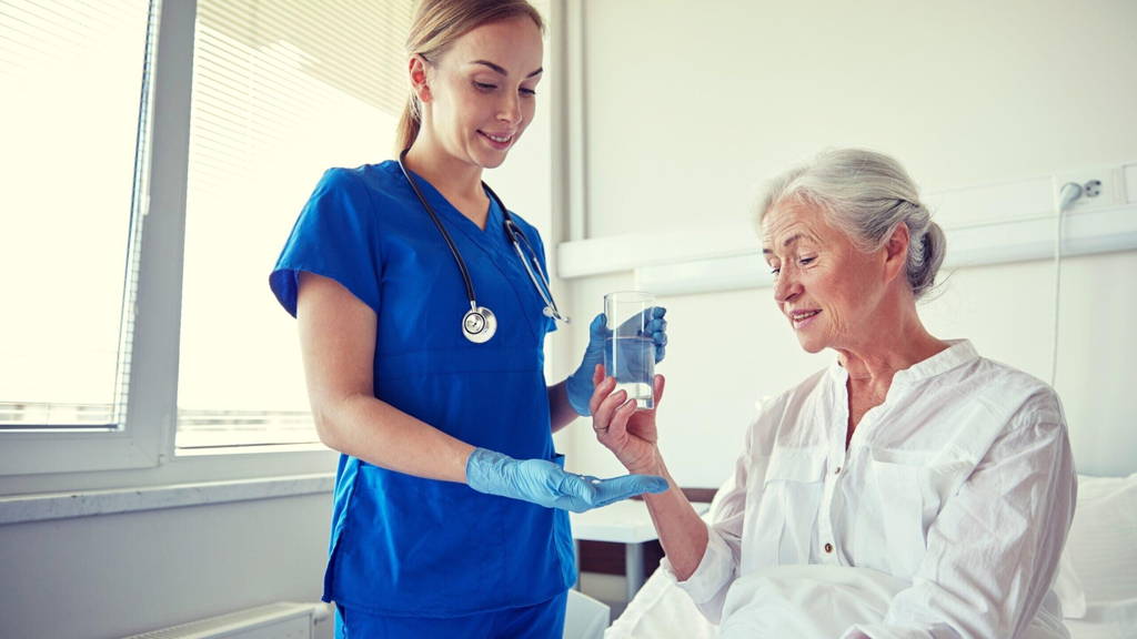 nurse giving medicine to senior woman at hospital