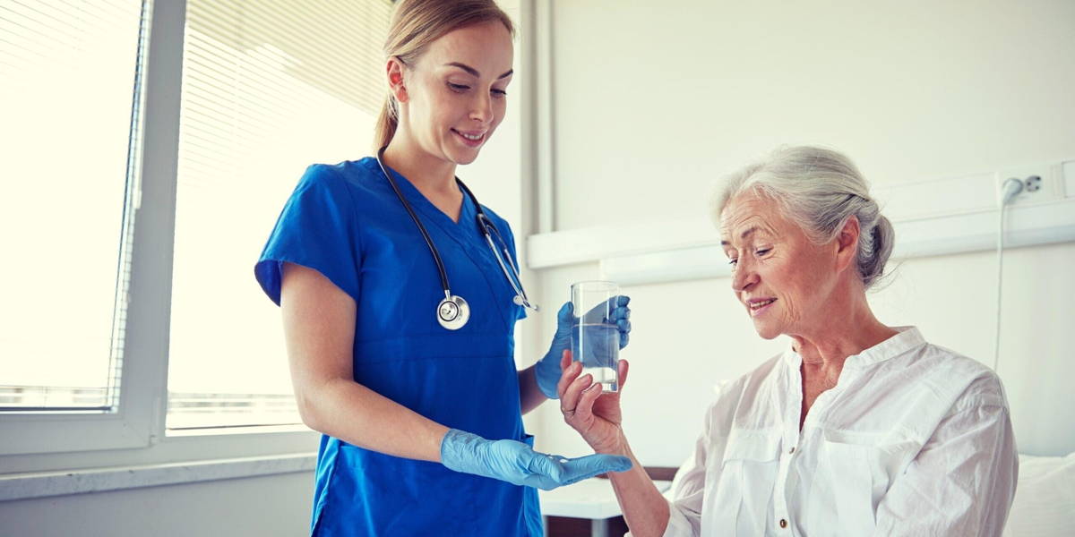 nurse giving medicine to senior woman at hospital