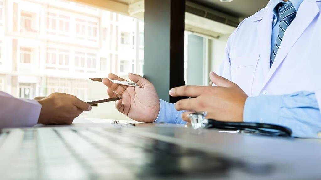 Two doctors discussing patient notes in an office pointing to a