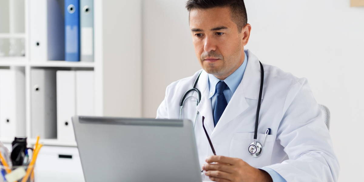 male doctor in white coat with laptop at hospital