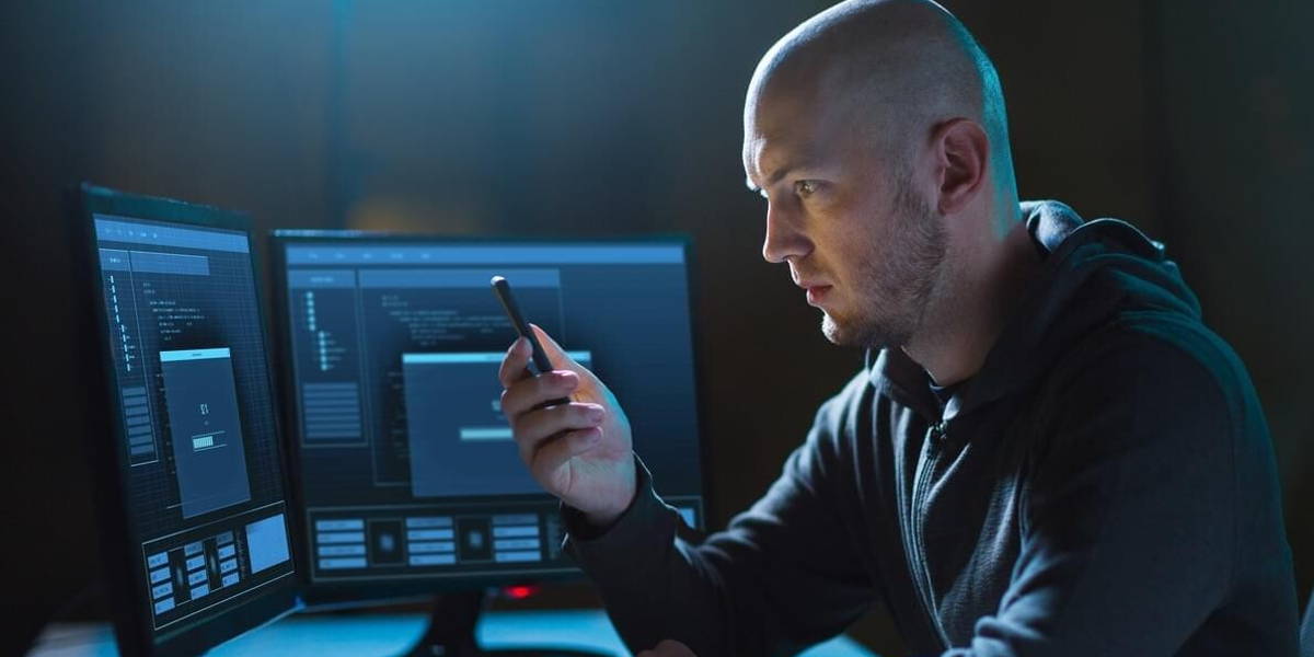hacker with smartphone and computers in dark room
