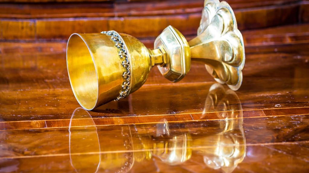 Golden grail turned on wooden background