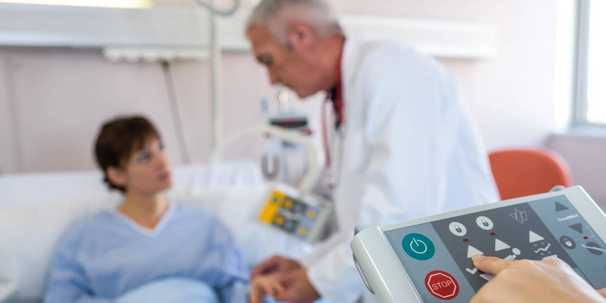 Doctor with patient, closeup of hand on bed controller