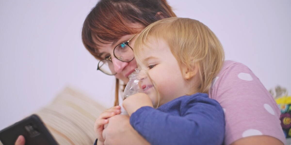 Kind met astma pomp kijkt naar smartphone