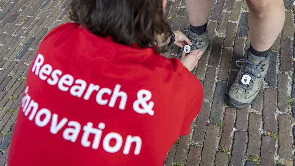 Foto-1_een-onderzoeker-bevestigt-de-sensoren-op-de-schoenen-van-een-wandelaar