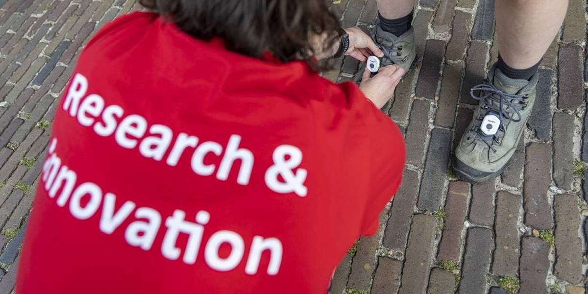Foto-1_een-onderzoeker-bevestigt-de-sensoren-op-de-schoenen-van-een-wandelaar