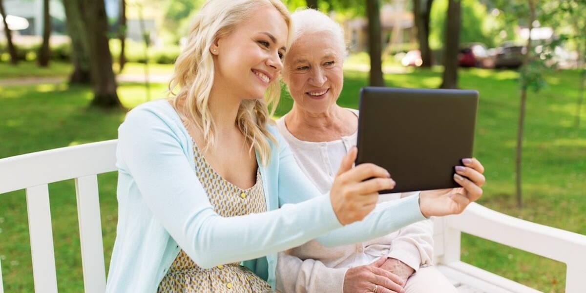 daughter with tablet pc and senior mother at park