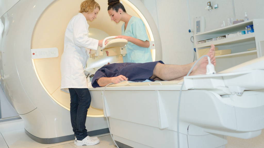 patient on mri machine while two female doctors operating it