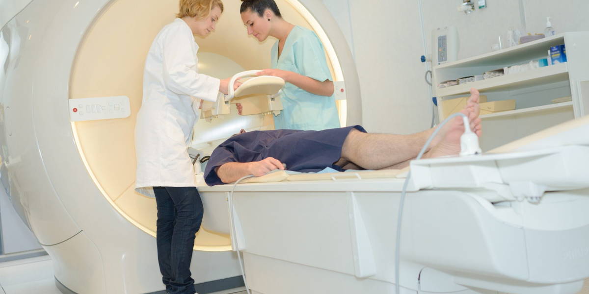 patient on mri machine while two female doctors operating it