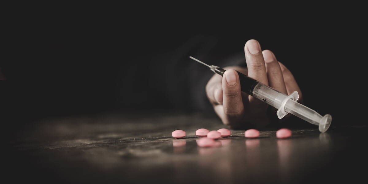 Hand met verslavende middelen: pillen en spuit
