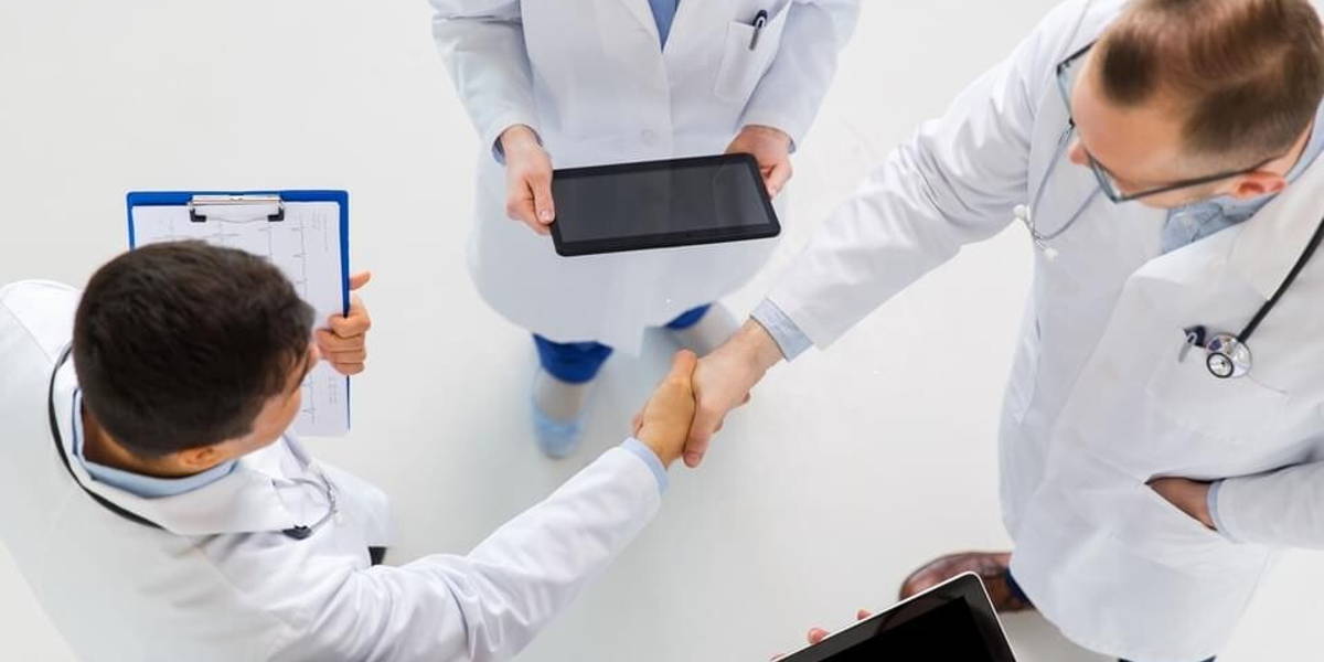 doctors with tablet pc doing handshake at hospital