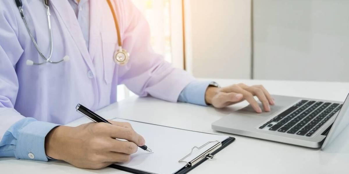 Close up of unknown male doctor sitting at the table near the wi