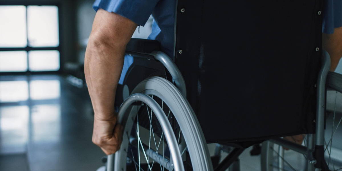 In the Hospital, Close-up Following Shot of the Elderly Man in the Wheelchair Moving through the Hallway.
