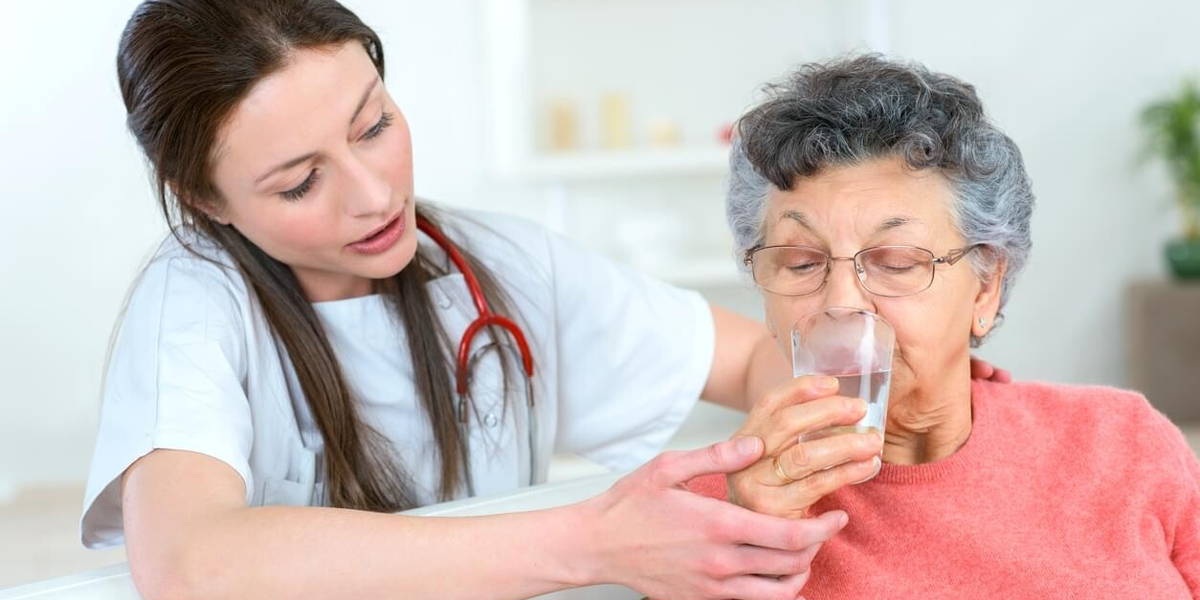 Giving senior woman a drink of water