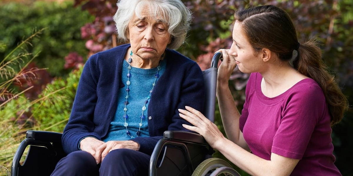 Adult Daughter Comforting Senior Mother In Wheelchair