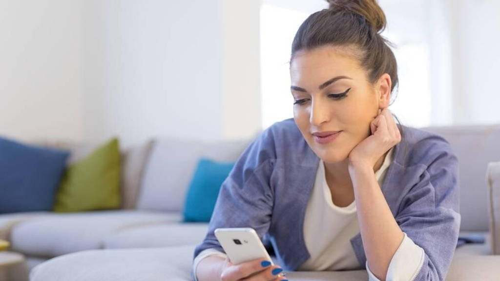vrouw-smartphone-thuis-vrolijk