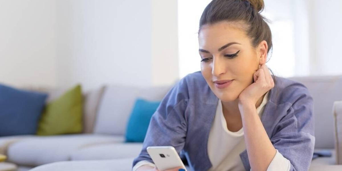 vrouw-smartphone-thuis-vrolijk