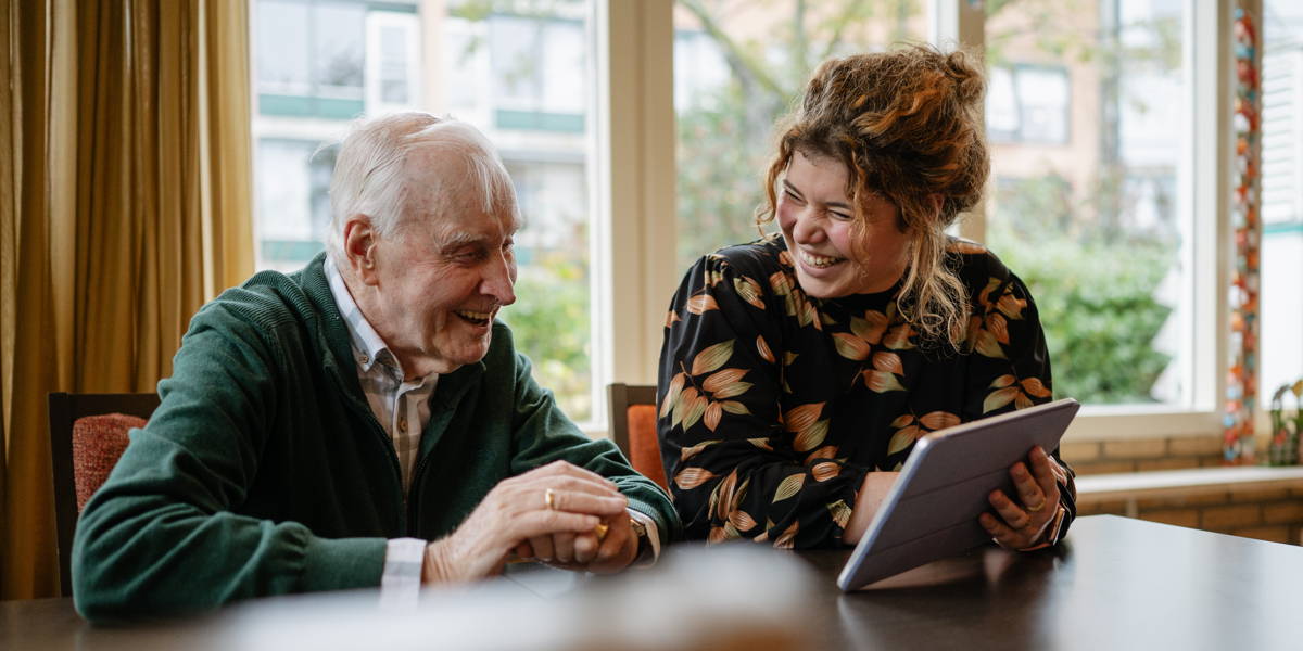 Oude man en jonge vrouw kijken naar IPad