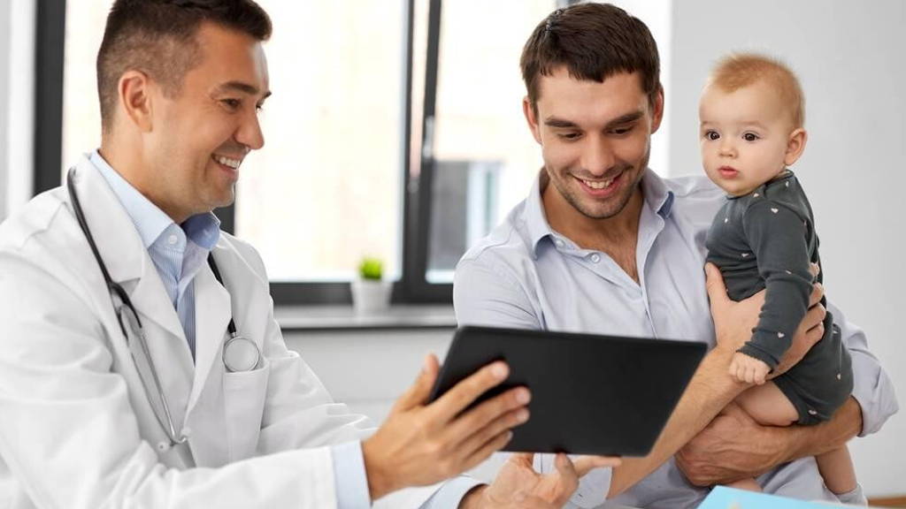 father with baby and doctor with tablet at clinic