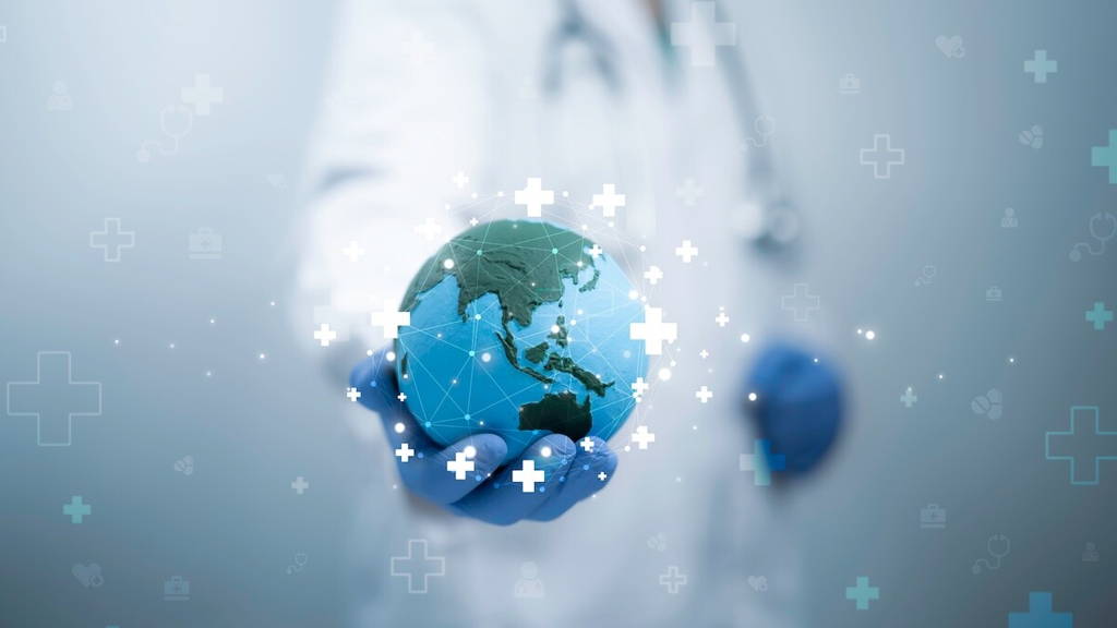 Close-up van een persoon in een witte doktersjas en blauwe handschoenen die een verlichte, blauwe wereldbol vasthoudt.