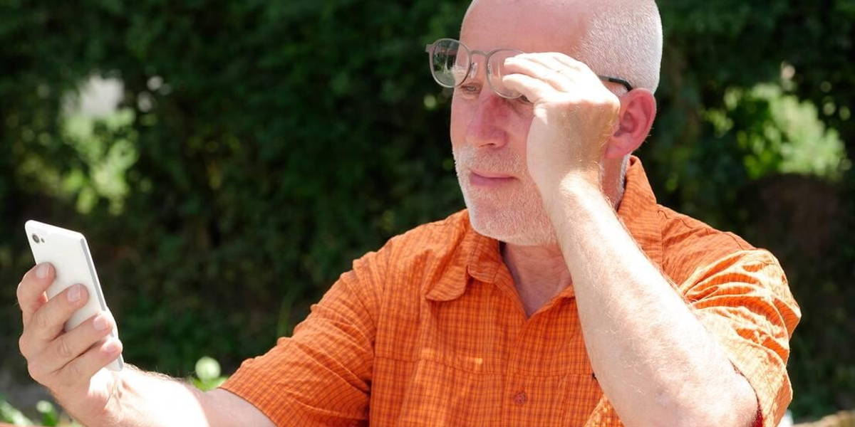 mature man has problems with his eyesight for reading on his sma