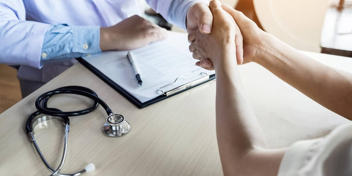 Doctor shakes hands at medical office with patient, wearing glas