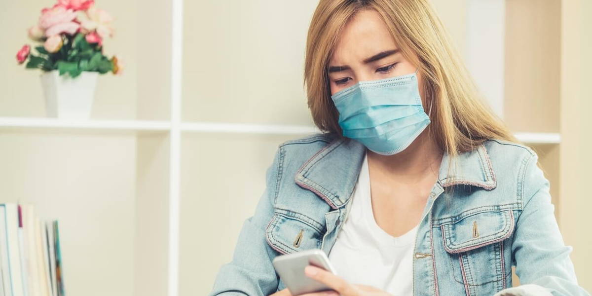 Quarantined woman working at home wearing face mask protect from Coronavirus.