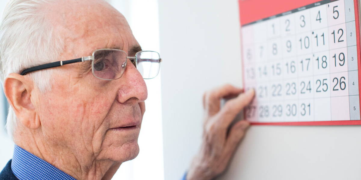 Confused Senior Man With Dementia Looking At Wall Calendar